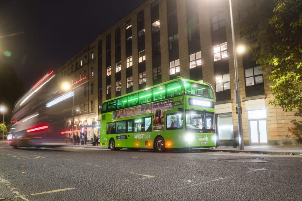 A green WEST bus stopped at a bus stop at night in Bristol City Centre