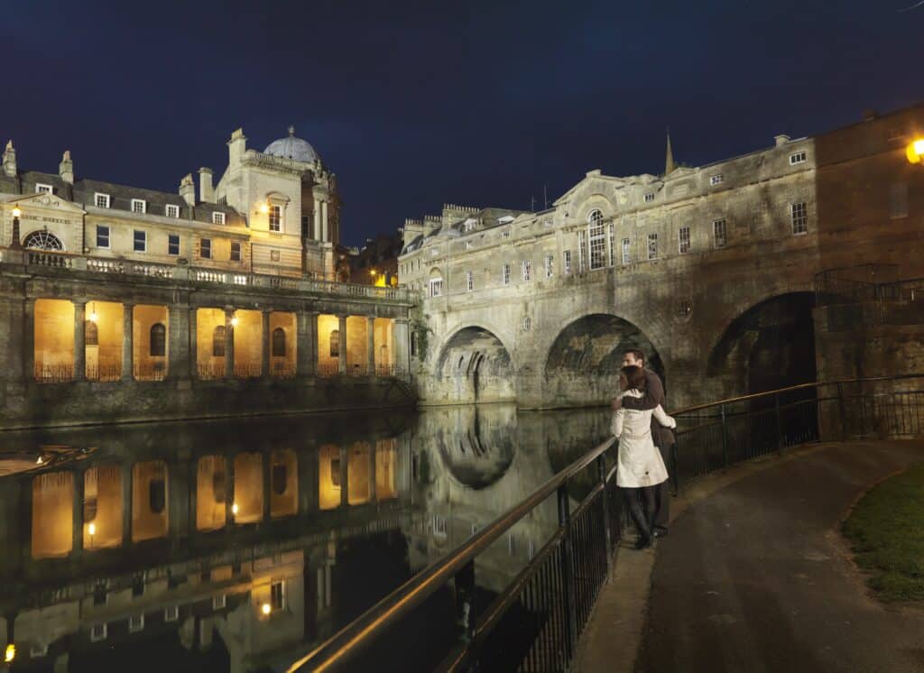 Bath at night with two people enjoying the view of the river.