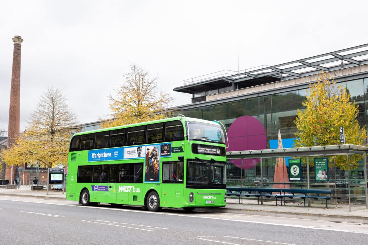A green WEST bus stopped outside a bus stop next to "We are the Curious" in Bristol City Centre