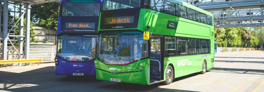 2 First bus double deckers one in blue and one in the WEST branded green with the wording "From diesel" "to electric" on the signage to promote the new Electric buses now in Bath.