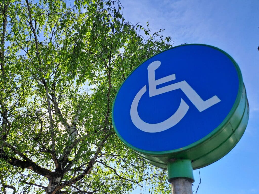 a blue circular disabled road sign with a tree in the backgroun